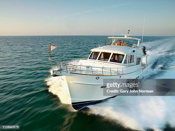 couple on yacht powering through sea - embarcación de recreo fotografías e imágenes de stock