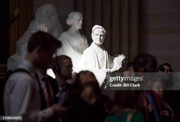 Beam of sunlight illumiates the Portrait Monument, depicting suffragists Elizabeth Cady Stanton, Susan B. Anthony and Lucretia Mott, as tourists...