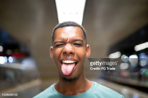 afro latinx young man making a face at the metro portrait - sticking out tongue stock pictures, royalty-free photos & images