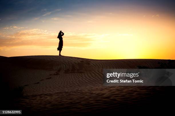 woman watching sunset in a desert silhouette - arab woman silhouette stock pictures, royalty-free photos & images