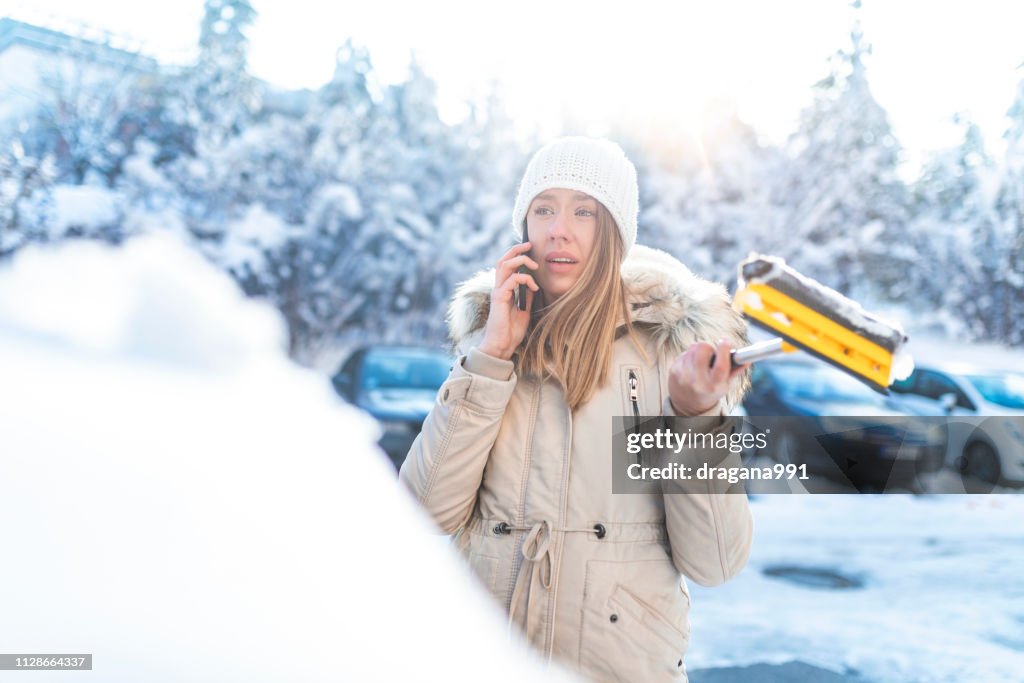 Young woman calling for help or assistance after her car breakdown in the winter.