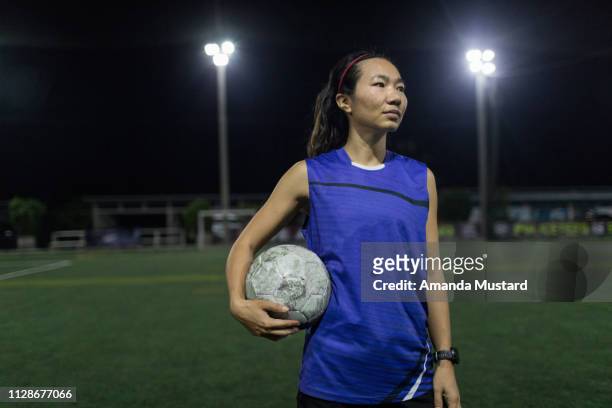 female thai soccer player standing on field with ball - akha woman stock pictures, royalty-free photos & images