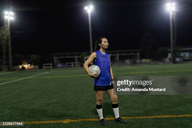 female thai soccer player standing on field with ball - akha woman stock pictures, royalty-free photos & images