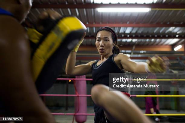 athletic akha/thai woman kicking in boxing ring - boxeo deporte fotografías e imágenes de stock