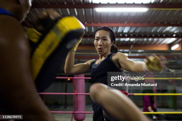 athletic akha/thai woman kicking in boxing ring - boxing womens ストックフォトと画像