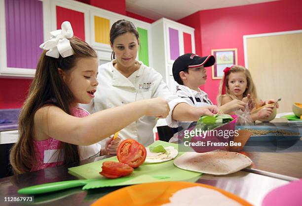Allie Foyerlicht, second from left, of Young Chefs International, helps Kennedy Silva-Costa far left, her brother Harrison center right, and Britton...