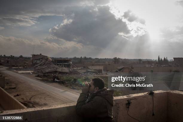 Syrian Democratic Forces commander looks for ISIL positions from a rooftop near the front line on February 10, 2019 in Bagouz, Syria. US-led...