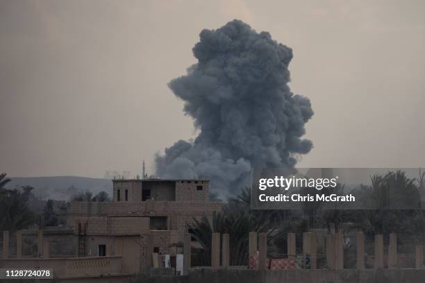 Smoke from an airstrike is seen over buildings near the front line on February 10, 2019 in Bagouz, Syria. US-led coalition airstrikes continued...