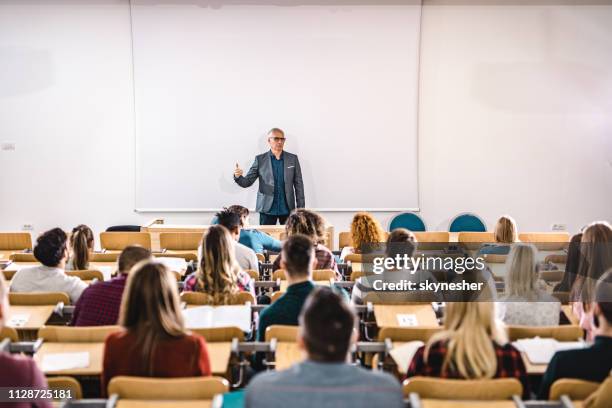 oberlehrer im gespräch mit großen gruppe von college-studenten im amphitheater. - university lecturer stock-fotos und bilder