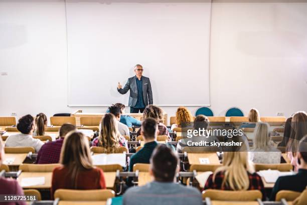 senior teacher talking to large group of college students in amphitheater. - education building stock pictures, royalty-free photos & images