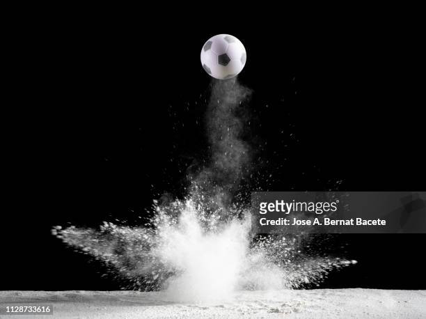 impact and rebound of a ball of soccer on a surface of land and powder on a black background - ballon rebond stock-fotos und bilder