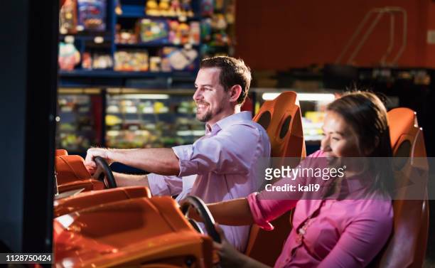 zwei erwachsene spielen in video-arcade-rennspiel - amusement arcade stock-fotos und bilder