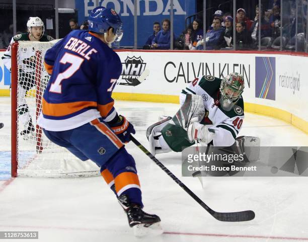 Devan Dubnyk of the Minnesota Wild shoots the puck away from the on-rushing Jordan Eberle of the New York Islanders during the second period at the...