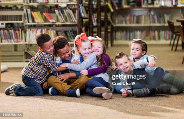 children in library, girl with down syndrome, group hug - down syndrome girl stock pictures, royalty-free photos & images
