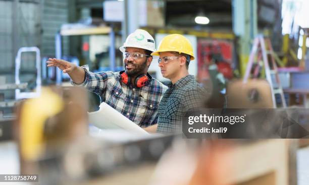 multi-ethnischen arbeiter in metall fabrikationsanlage sprechen - schutzhelm stock-fotos und bilder