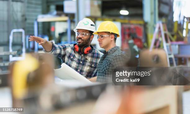 multi-ethnic workers talking in metal fabrication plant - factory imagens e fotografias de stock