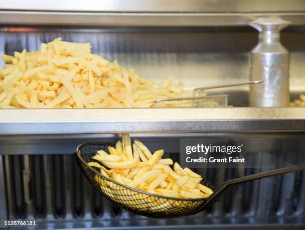 close up of french fries cooking. - deep fried stockfoto's en -beelden