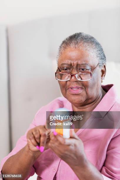 mujer senior afroestadounidense con botella - entrecerrar los ojos fotografías e imágenes de stock