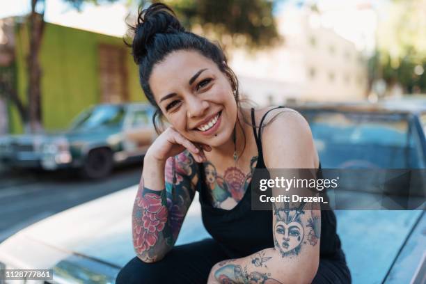 Retrato de hermosa Latina /Mexican milenaria mujer con tatuajes sentado en la capilla del coche