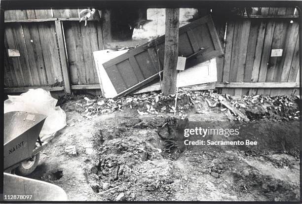 In this November 14, 1988 file photograph, signs on the fence mark the backyard gravesites at 1426 F Street in Sacramento, California where police...