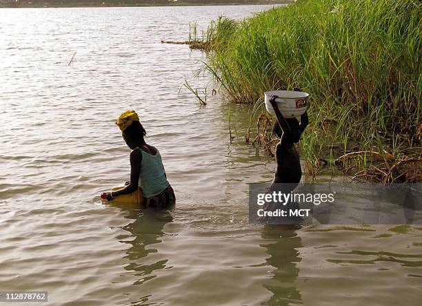 Young girls fetch lake water for their village on the banks of Lake Chad. One of the largest lakes in the world, central Africa's Lake Chad, is...