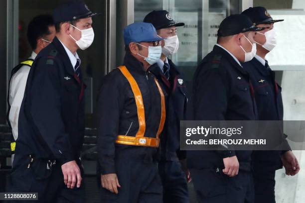 Former Nissan chairman Carlos Ghosn is escorted as he walks out of the Tokyo Detention House following his release on bail in Tokyo on March 6, 2019....