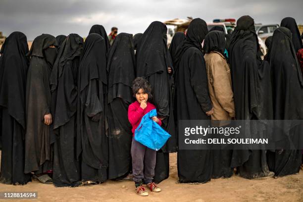 Fully-veiled women and children queue at a screening point as hundreds of civilians, who streamed out of the Islamic State group's last Syrian...