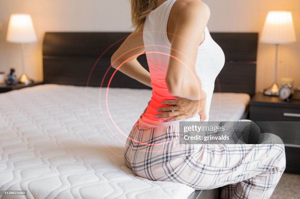 Woman suffering from back pain because of uncomfortable mattress