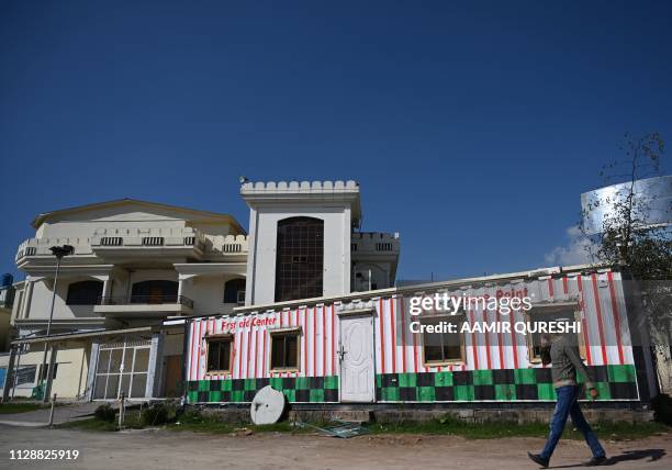 Pakistani man walks past a closed medical dispensary and offices of the Falah-e-Insaniat Foundation -- an organisation believed by the UN to be a...