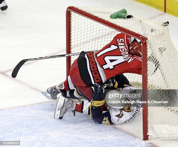 After getting poke checked by the Carolina Hurricanes goalie Cam Ward, the Buffalo Sabres' Jason Pominville crashes into the net with the Hurricanes'...