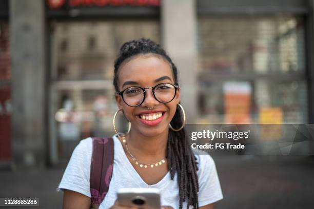 afro junge frau in der stadt mit smartphone-porträt - alternative lifestyles stock-fotos und bilder