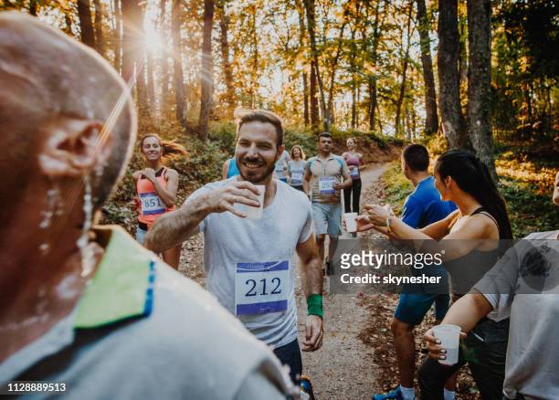 Athletic people running a marathon and refreshing themselves with water.