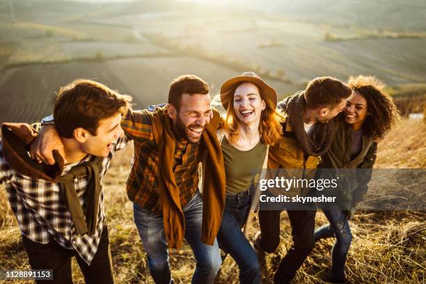 young cheerful friends walking up the hill in autumn day. - friendly hills stock pictures, royalty-free photos & images