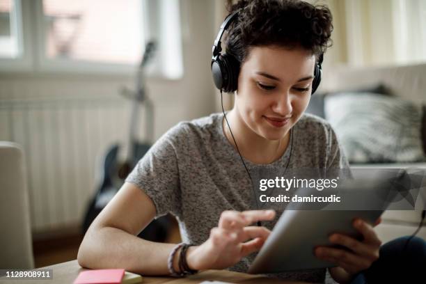 woman at home using a tablet computer - how to upload fotos imagens e fotografias de stock