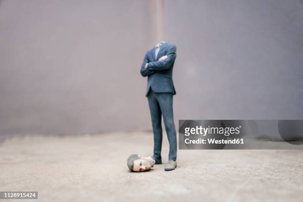 headless businessman figurine standing on cocrete - headless stock-fotos und bilder