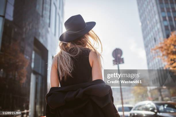 back view of woman with hat dressed in black - spogliarsi foto e immagini stock