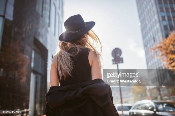 back view of woman with hat dressed in black - uitkleden stockfoto's en -beelden