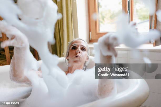 portrait of woman in bathtub playing with foam - badezimmer frau stock-fotos und bilder