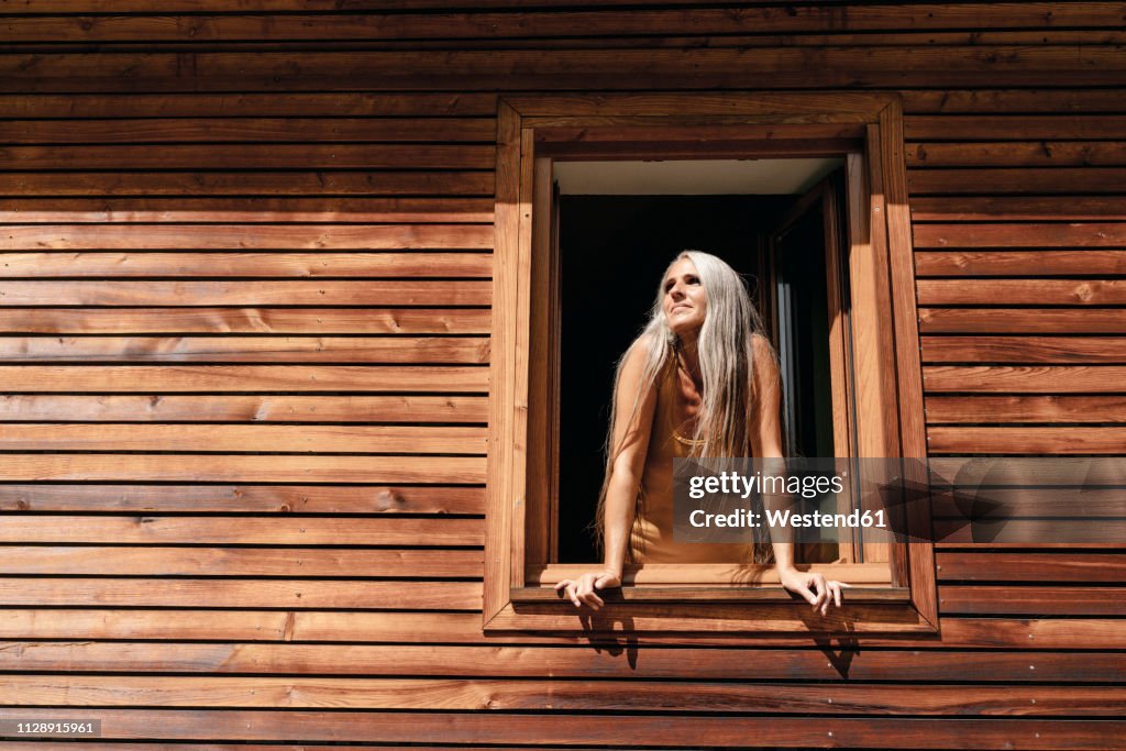 Woman looking out of window of her house