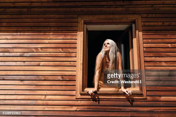 woman looking out of window of her house - leaning stock pictures, royalty-free photos & images