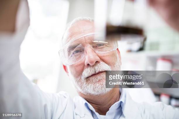 man looking at beaker in laboratory - examination closeup stock pictures, royalty-free photos & images