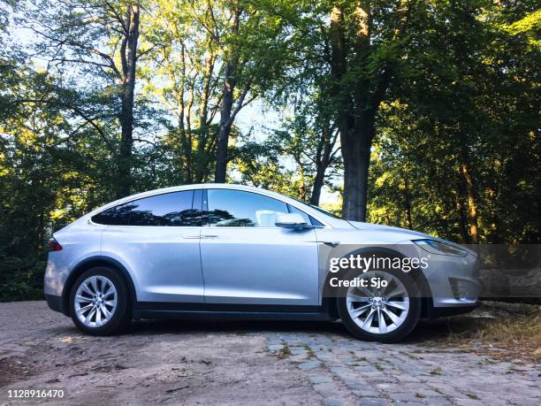 futuristic tesla model x electric car parked in a forest - tesla model s stock pictures, royalty-free photos & images