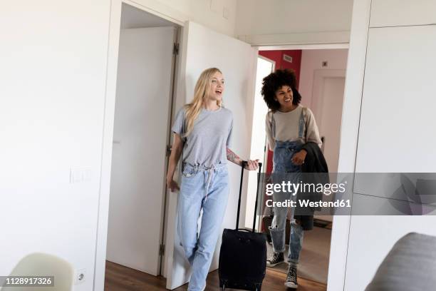 two happy women with baggage arriving in accomodation - girlfriend stockfoto's en -beelden