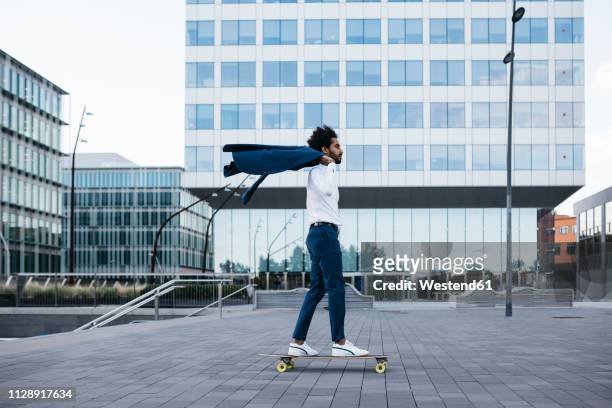 spain, barcelona, young businessman riding skateboard in the city - schnelligkeit stock-fotos und bilder