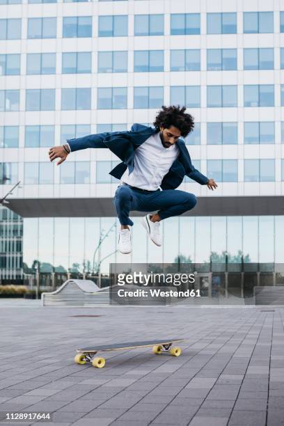 spain, barcelona, young businessman doing skateboard tricks in the city - hip hopper stock-fotos und bilder