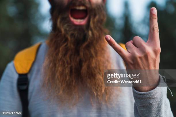 close-up of screaming man with beard making horn sign - rock n roll foto e immagini stock