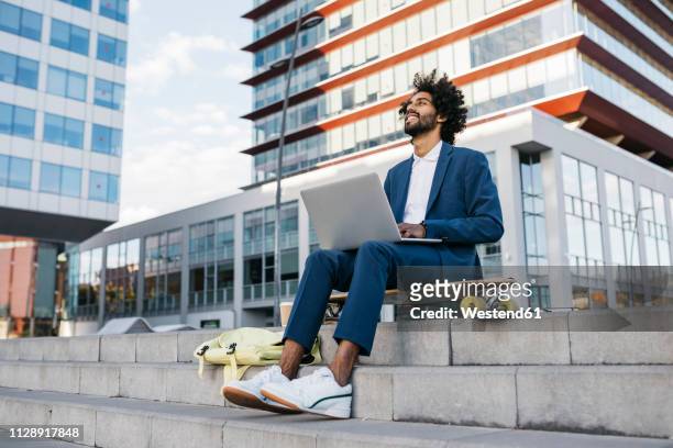 spain, barcelona, young businessman sitting outdoors in the city working on laptop - flexibility fotografías e imágenes de stock