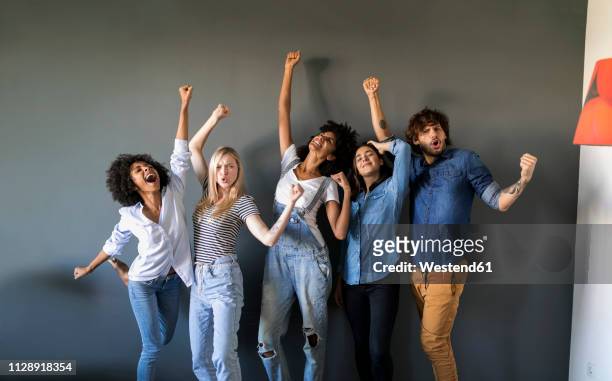 group portrait of friends standing at a wall cheering - cheering stock-fotos und bilder