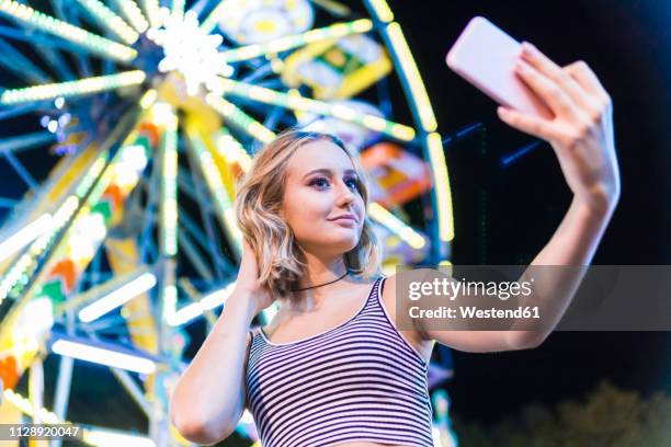 portrait of teenage girl taking selfie in front of big wheel at fair - alleen één tienermeisje stockfoto's en -beelden