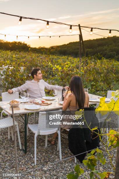 italy, tuscany, siena, young couple having dinner in a vineyard - siena italy stockfoto's en -beelden